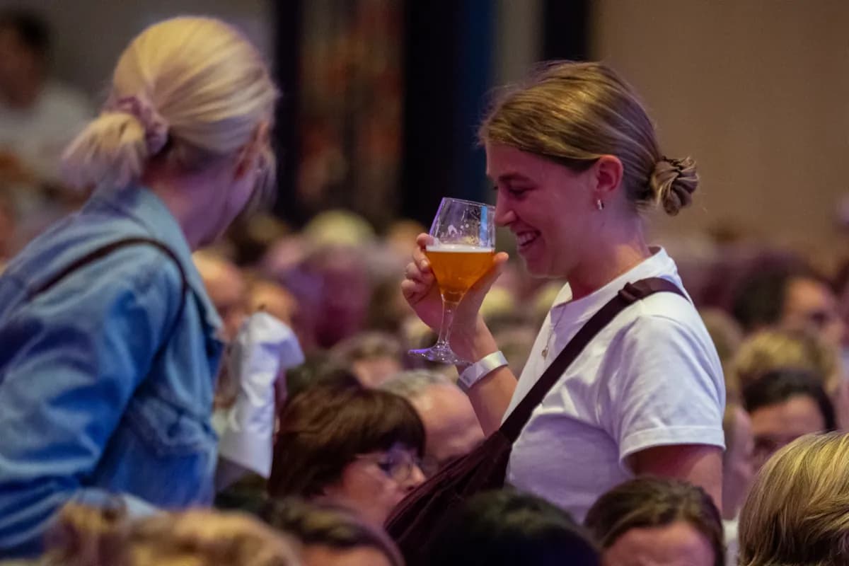 Une spectatrice rit, un verre de bière à la main, au milieu du public